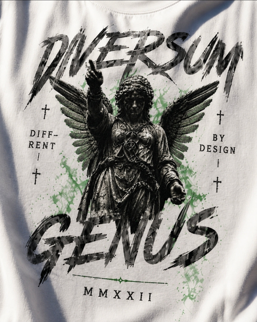 White graphic t-shirt featuring a distressed black illustration of an angel with wings and the text 'DIVERSUM GENUS' with 'MMXXII' below, accented with light green paint splatters.